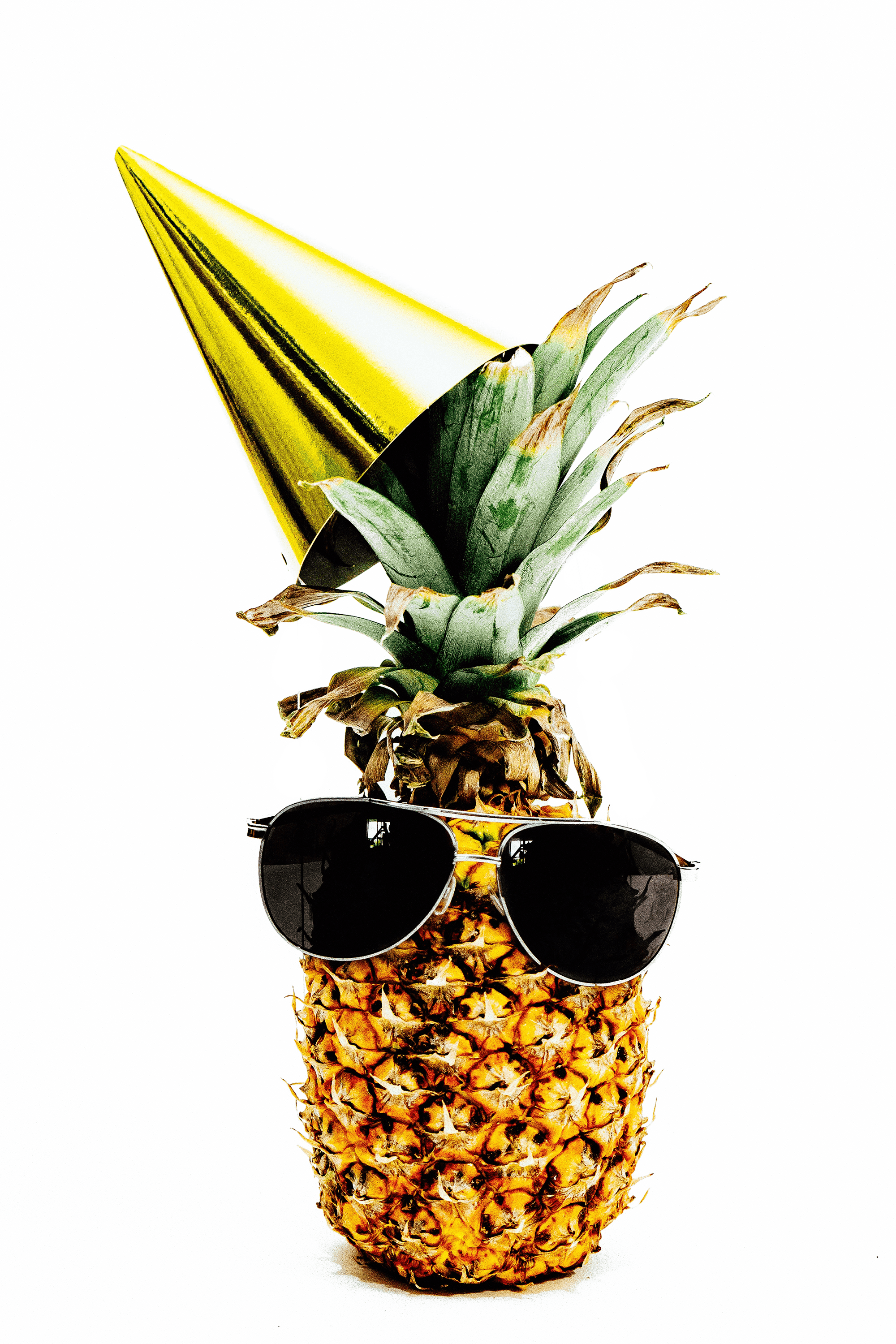Ananas, die eine Sonnebrille und einen goldenen Partyhut trägt.